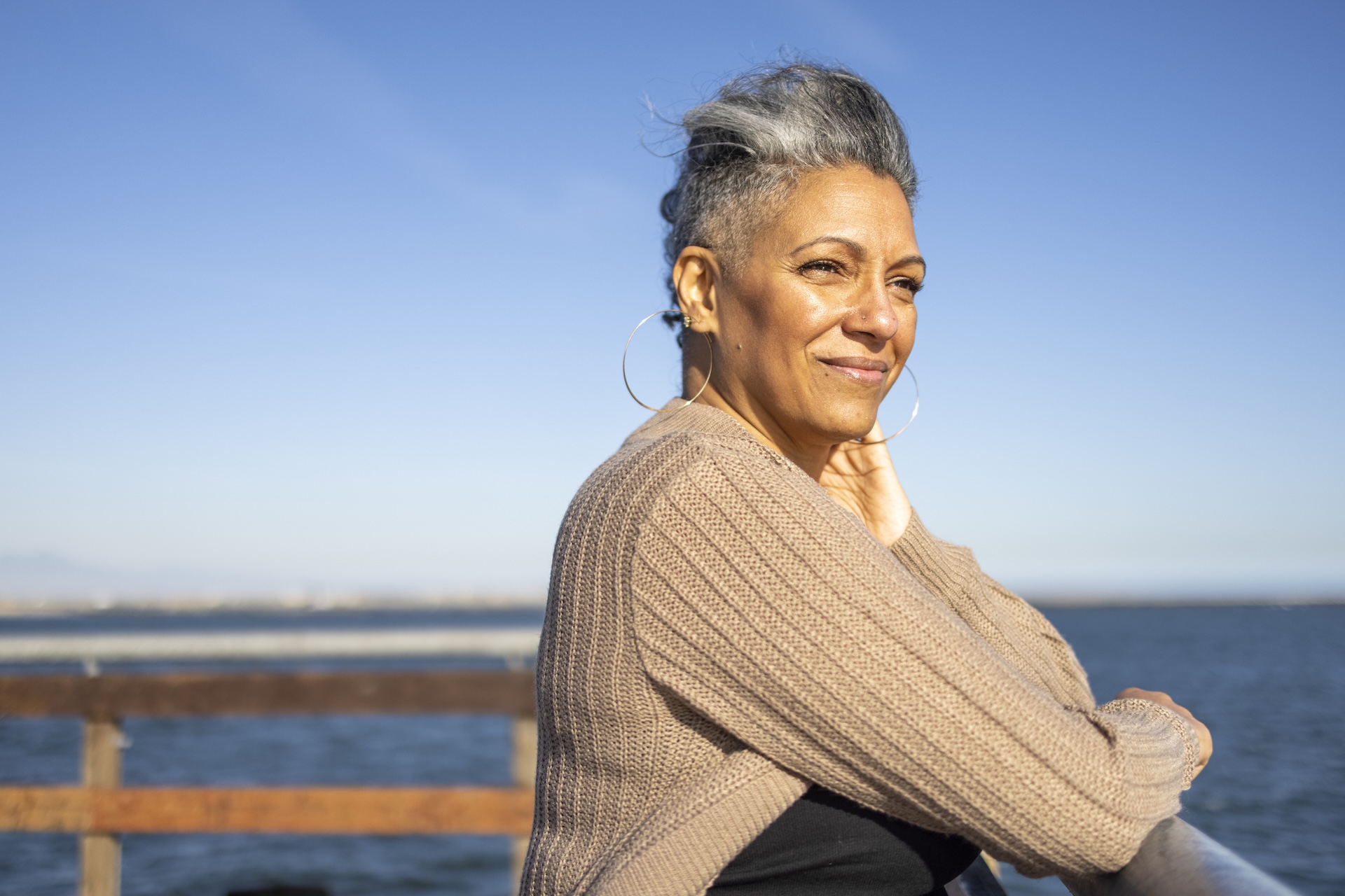 A mature black woman relaxes on the pier at the beach.